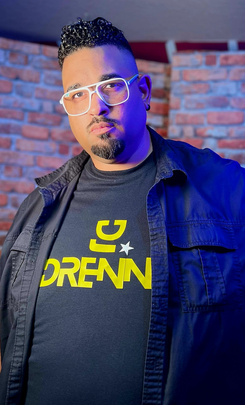 DJ Adrennaa wearing glasses and a t-shirt with the name DJ Adrennaa on it