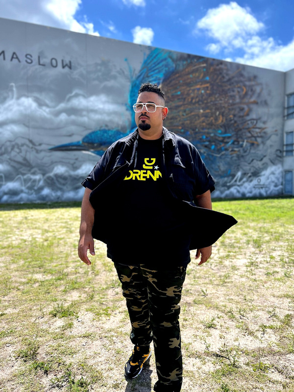 DJ Adrennaa standing in front of a mural with a bird on it