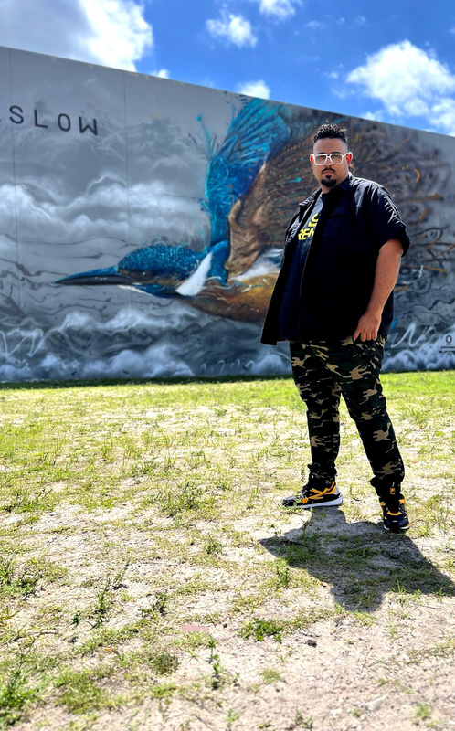 Dj Adrennaastanding in front of a mural of a bird